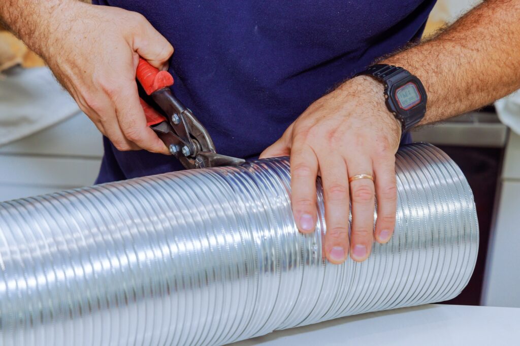 Man used scissors to cutting flexible aluminum corrugated pipe for a vent air duct
